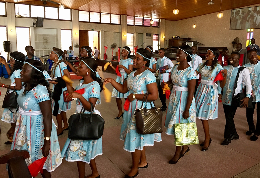 A group of women in traditional uniform parade through the room.